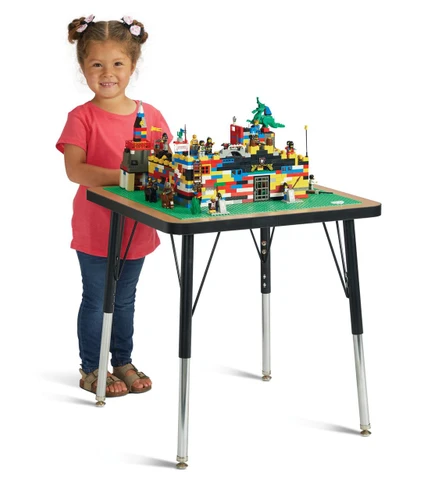 Jonti-Craft Adjustable Building Table - Traditional Brick Compatible - 15-24H, young girl with pigtails and pink shirt standing next to a table with a colorful LEGO castle construction.