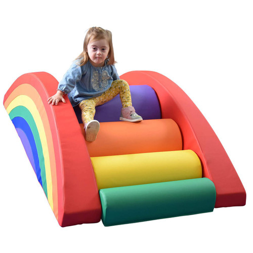 Children's Factory Rainbow Arch Soft Play Climber, colorful rainbow-themed soft play climbing structure with a toddler girl sitting on top.