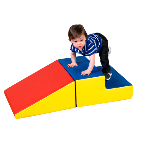 Children's Factory Basic Play Set Soft Play Climber, a young boy crawling on a colorful foam climber with red, blue, and yellow sections for safe indoor play.