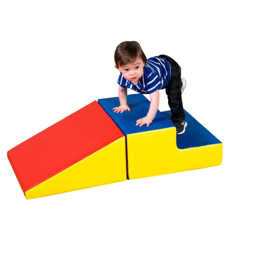 Children's Factory Basic Play Set Soft Play Climber, a young boy crawling on a colorful foam climber with red, blue, and yellow sections for safe indoor play.