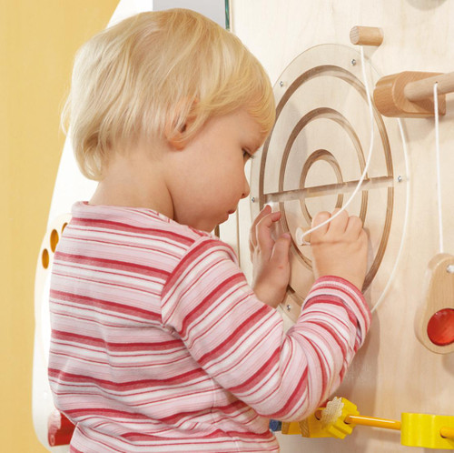 HABA Pro Sensory Learning Wall 'Curve A' Wall Panel Toy, a wooden sensory wall panel with concentric circles and various interactive wooden and string elements for early childhood sensory development.