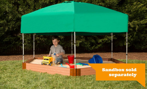 Frame It All Telescoping Hexagon Sandbox Canopy & Cover, child playing in a hexagon-shaped sandbox with a green canopy and cover, outdoor setting with green trees in the background.