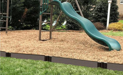 Frame It All Weathered Wood Straight Playground Border 16' - 1" Profile, brown wooden garden edging border around a children's play area with a slide and swings on a backyard playground.