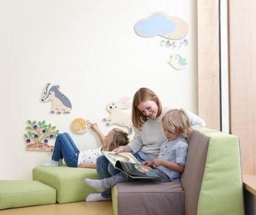 HABA Pro Cloud Wooden Play Wall Decoration, child-friendly decor featuring clouds, animals, and nature-themed wooden wall ornaments in a children's playroom.