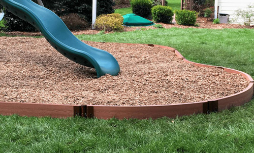Frame It All Classic Sienna Curved Playground Border 16' - 2" Profile, brown curved plastic border surrounding a playground with mulch and a slide.