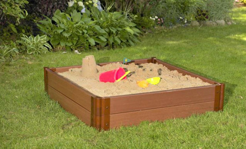 Frame It All Square Sandbox with Collapsible Cover - 4' x 4' x 11'', a wooden square sandbox filled with sand, outdoor backyard setting with green grass and plants.