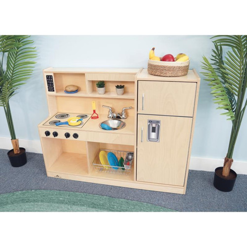 Whitney Brothers Let's Play Toddler Play Kitchen Combo - Natural, wooden toy kitchen with stove, sink, fridge, and storage compartments, accompanied by plastic play dishes and utensils.