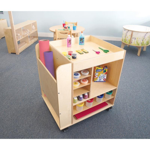 Whitney Brothers Rolling Mobile Art Cart, wooden art cart with multiple shelves and compartments, filled with art supplies like paint jars and paper roll, designed for children's art activities.