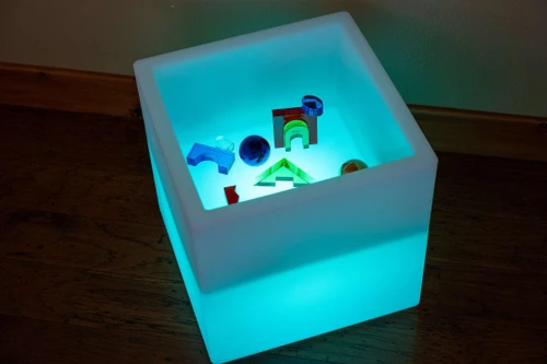 TickiT Sensory Mood Light Play Cube, illuminated white cube with colorful sensor toys inside.