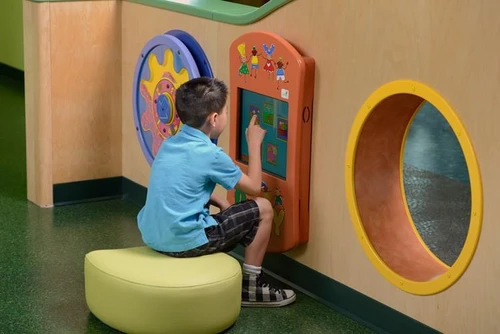 Playscapes Keydo Interactive Touch Screen Activity Wall Panel, child engaging with educational digital games on the touchscreen in a playful environment.