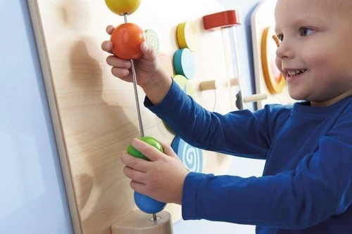HABA Pro Motor Skills E Sensory Learning Wall Panel, young boy engaging with colorful sensory and motor skills development wall panel.