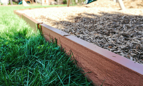 Frame It All Classic Sienna Straight Playground Border 16' - 2" Profile, close-up view of the wooden playground border on the grass and wood chip surface.