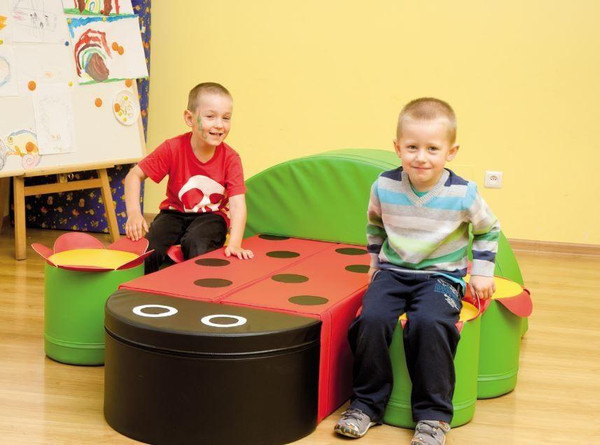 Novum Ladybug Soft Play Table & Seating Set, colorful ladybug-themed play furniture with two young children playing on it in a bright playroom.