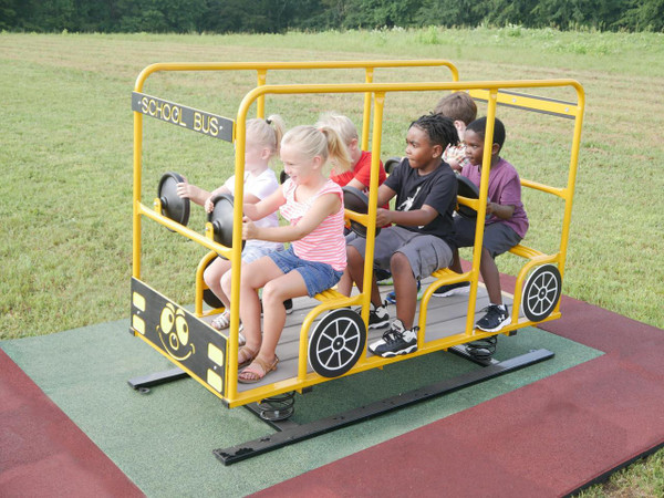 Infinity Playgrounds Happy Time School Bus Spring Rider, children sitting on a yellow school bus-shaped playground spring rider with steering wheels in an outdoor park.