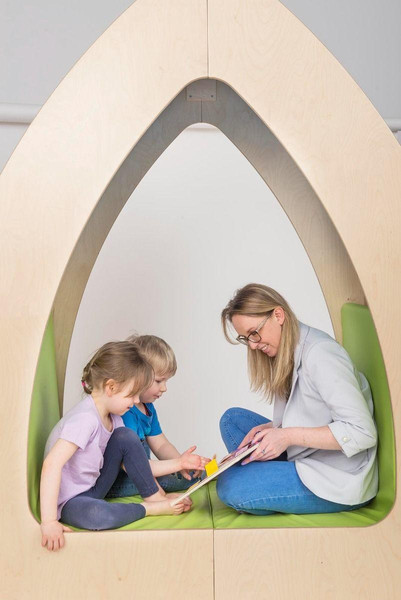 Moje Bambino Reading Oasis Library with Shelves, children and a librarian reading together in a cozy wooden nook with green cushions