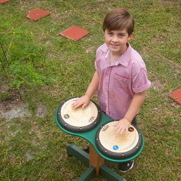 Playmore Designs DouBBle Play Drum Table, a young boy playing drums outdoors on a green table with two drum pads.