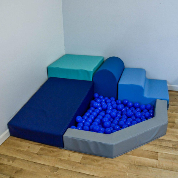 Children's Factory Mikayla's Mini Mountain Tranquility Foam Ball Pit, colorful soft foam climbing and sitting blocks with a ball pit filled with blue plastic balls.