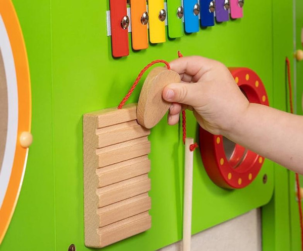 SPARK & WOW Percussion Wooden Mallet, replacement for Crocodile & Elephant Wall Toy, with a wooden mallet being held in a child's hand near a colorful musical toy wall.