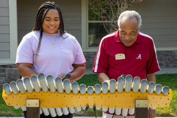 Freenotes Imbarimba 22 Note Outdoor Marimba, two people playing the outdoor marimba instrument with metal tubes in a yard.