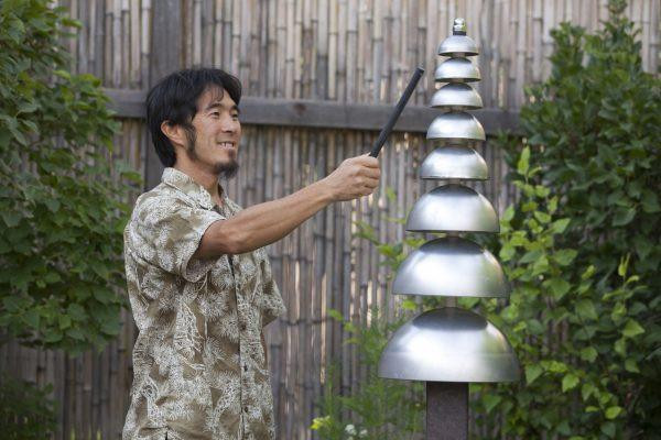 Freenotes Pagoda Bells, person playing musical bells outdoors in a garden setting.