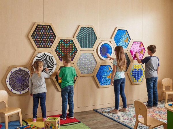 LiteZilla Multi-Sensory Hexagon Panel - Gyro Rings XL, interactive sensory play panels on wall with children exploring and touching the different textured and colorful surfaces.