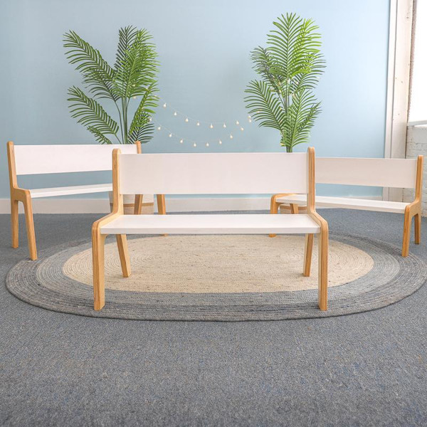 Whitney Brothers Whitney Plus White Bench - 12H, white wooden bench with natural wood legs, placed on a circular rug with green plant decorations in the background.