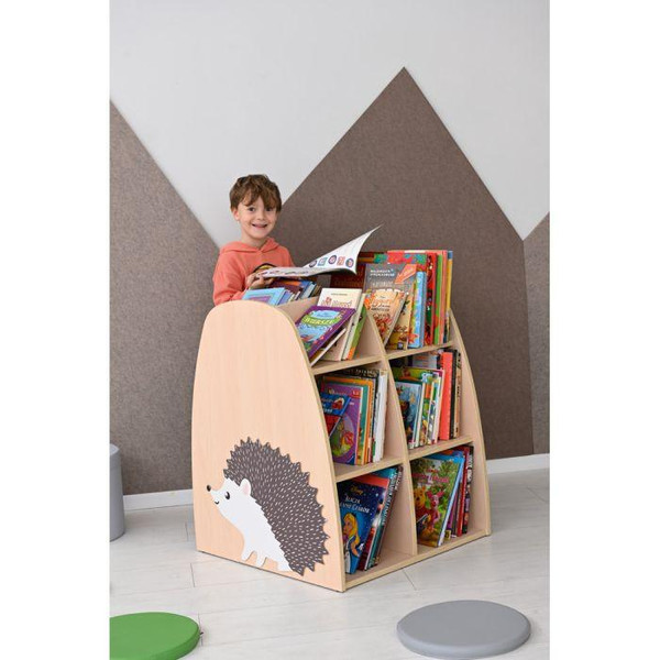 Moje Bambino Double Sided Hedgehog Bookcase, children's wooden storage unit with a cute hedgehog illustration on the side, filled with colorful children's books, in a modern room with geometric wall decor.