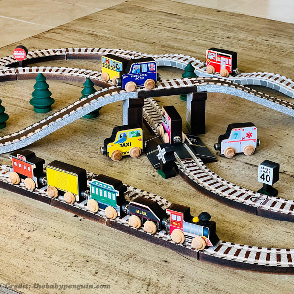 Maple Landmark Town Wooden Train Set, colorful wooden toy train on track with miniature trees, signs, and various train cars including ambulance, taxi, and police vehicles.