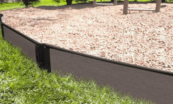Frame It All Weathered Wood Straight Playground Border 16' - 1" Profile, durable wood border installed around a playground area, with grass on one side and mulch on the other.