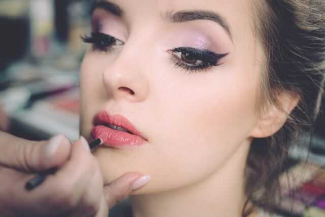 Woman having lipstick applied professionally
