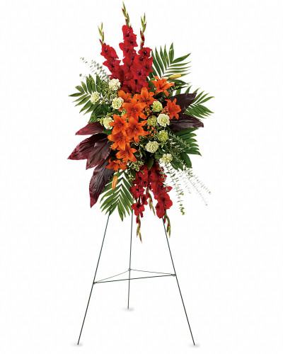 While the loved one is no longer present, there are happy times that will never be forgotten. This radiant spray of red and orange flowers will be a lovely reminder.  The stunning arrangement includes orange Asiatic lilies, red gladioli, green carnations, peach hypericum, emerald palm and red ti leaves, accented with assorted greenery.
