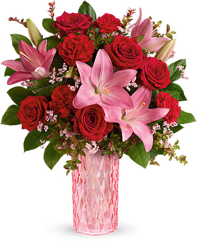 An elegant Valentine's Day delight, this romantic, diamond-cut glass vase is the prettiest shade of pink--the perfect complement for ravishing red roses and pink lilies.
This bouquet features red roses, pink asiatic lilies, red carnations, pink limonium, red huckleberry and lemon leaf. 