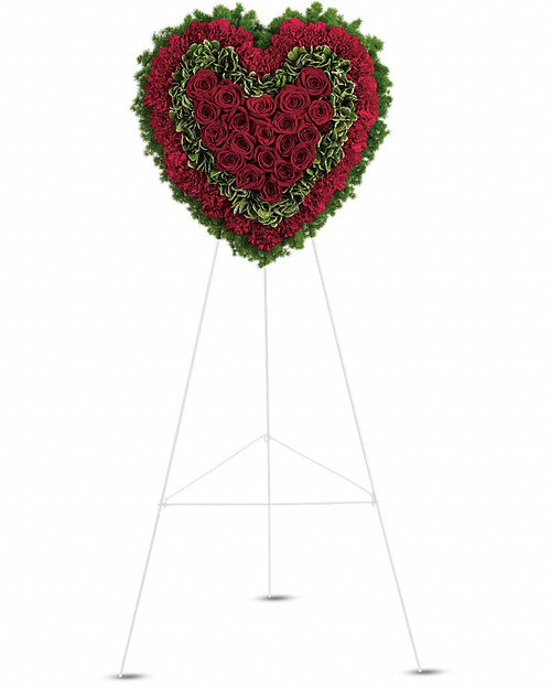 Remember a loved one's generous heart with this red arrangement in a classic heart shape, a declaration of eternal love and devotion.
Speak from your heart. This majestic funeral display is a charming, heartfelt way to express your love, composed of sympathy red roses and carnations with variegated pittosporum and ming fern.  Red carnations, red roses, variegated pittosporum and ming fern are arranged into a touching heart design that's presented on a wire easel.