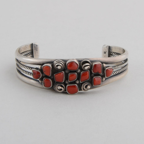 Sterling silver cuff with open rope work on sides, red coral with silver rosettes on top.