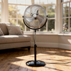 18 inch chrome pedestal fan standing in a bright living room next to a bay window