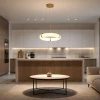 Alabaster ring pendant light glowing warmly above an open-plan kitchen island with wood and white cabinetry