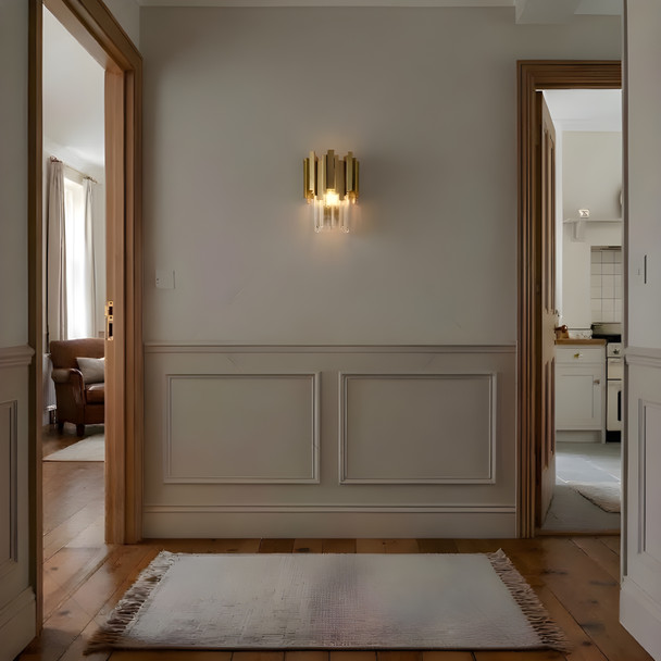 Gold crystal wall light with brass accents in a British hallway interior