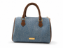 The Denim Boston Bag features soft, misty blue light wash denim, premium dark brown vegan leather trim, and polished gold-tone hardware.