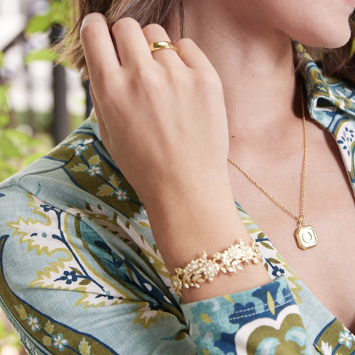 Elegant 18kt. matte gold plated cuff bracelet featuring intricate floral detailing, sparkling glass crystals and classic faux pearls in a refined Lowcountry designer style.