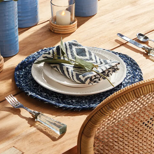 "Add a touch of eco-friendly flair to your dining experience with our recycled denim braid placemat from Napa Home & Garden. Featuring a timeless design and a hint of blue, it effortlessly complements any tablescape. Perfect for indoor use, simply dust with a soft cloth for maintenance. Dimensions: 15 x 15 x .25"