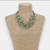 Turn heads with the handmade Atasi Statement Necklace, featuring soft pastel blue glass crystal beads woven through multi-strand vintage gold silk rope for an effortlessly elegant layered look. This lightweight chunky necklace is the perfect accessory for spring and summer outfits, bridal events, beach vacations, brunch, and everyday elevated style. Designed for women who love artisan jewelry, unique statement necklaces, and timeless boutique fashion, this handcrafted piece adds sophisticated texture and color to dresses, linen tops, and casual denim looks alike.