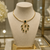The Rayne Necklace is a bold emerald green statement necklace featuring sculpted geometric details, luminous glass crystals, and vintage-inspired 14k gold plated hardware for a timeless, elegant look. Designed for women who love unique boutique jewelry, this adjustable gold collar necklace is perfect for weddings, holiday parties, special occasions, and elevated everyday style