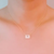 Woman wearing a gold emerald cut pendant necklace with an elegant outfit