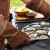 Set of 2 Outset Brown Leather Grill Gloves 15" Lifestyle pic with man wearing gloves and taking something off the grill