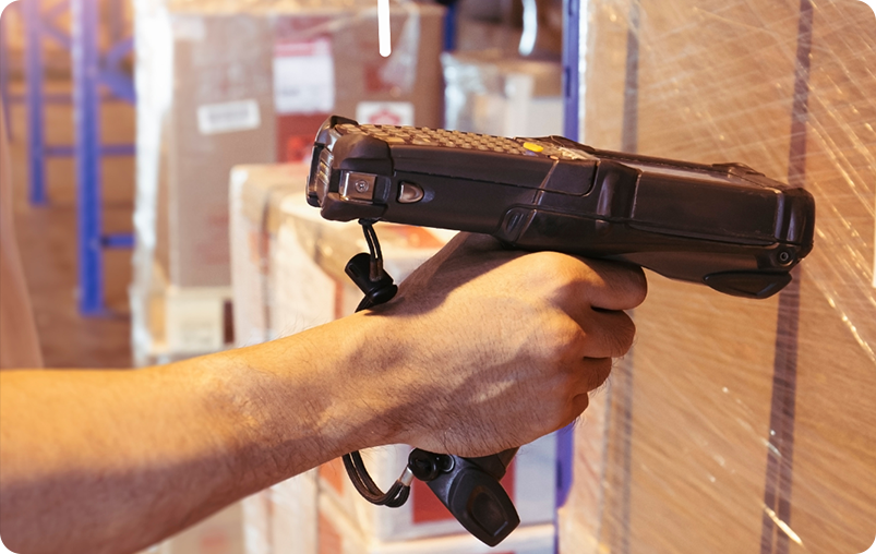 man in a warehouse scanning the barcode on a box with a barcode scanner gun