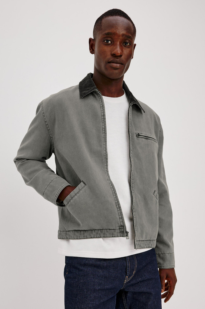 The Rails Morro Jacket in Graphite is a men's heavy cotton canvas duck utility jacket with a garment-dyed finish. It features a classic corduroy collar, a zip chest pocket, side welt pockets, and workwear shank button tabs at the back hem.