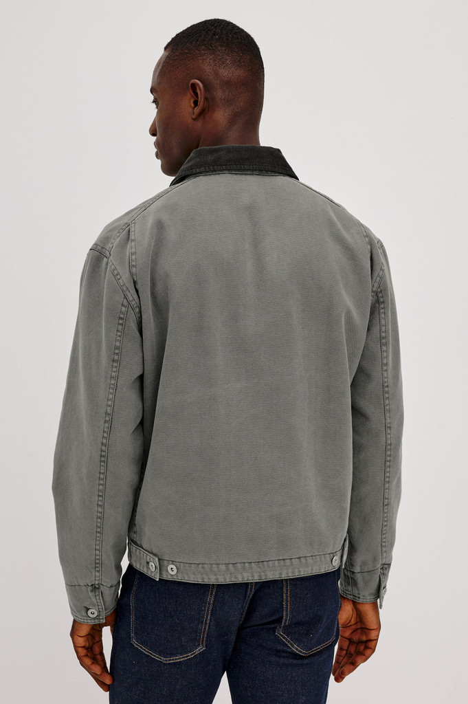 The Rails Morro Jacket in Graphite is a men's heavy cotton canvas duck utility jacket with a garment-dyed finish. It features a classic corduroy collar, a zip chest pocket, side welt pockets, and workwear shank button tabs at the back hem.