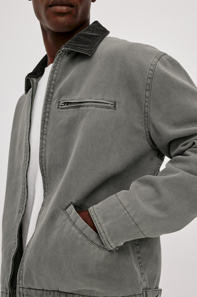 The Rails Morro Jacket in Graphite is a men's heavy cotton canvas duck utility jacket with a garment-dyed finish. It features a classic corduroy collar, a zip chest pocket, side welt pockets, and workwear shank button tabs at the back hem.