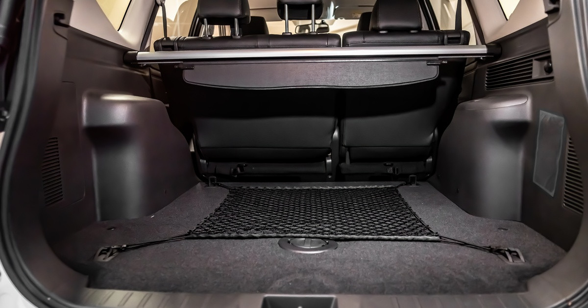 A close-up of the cargo space of a vehicle. A net is attached at four points on the surface of the cargo area.
