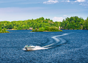 Speed boat racing across water with island in background